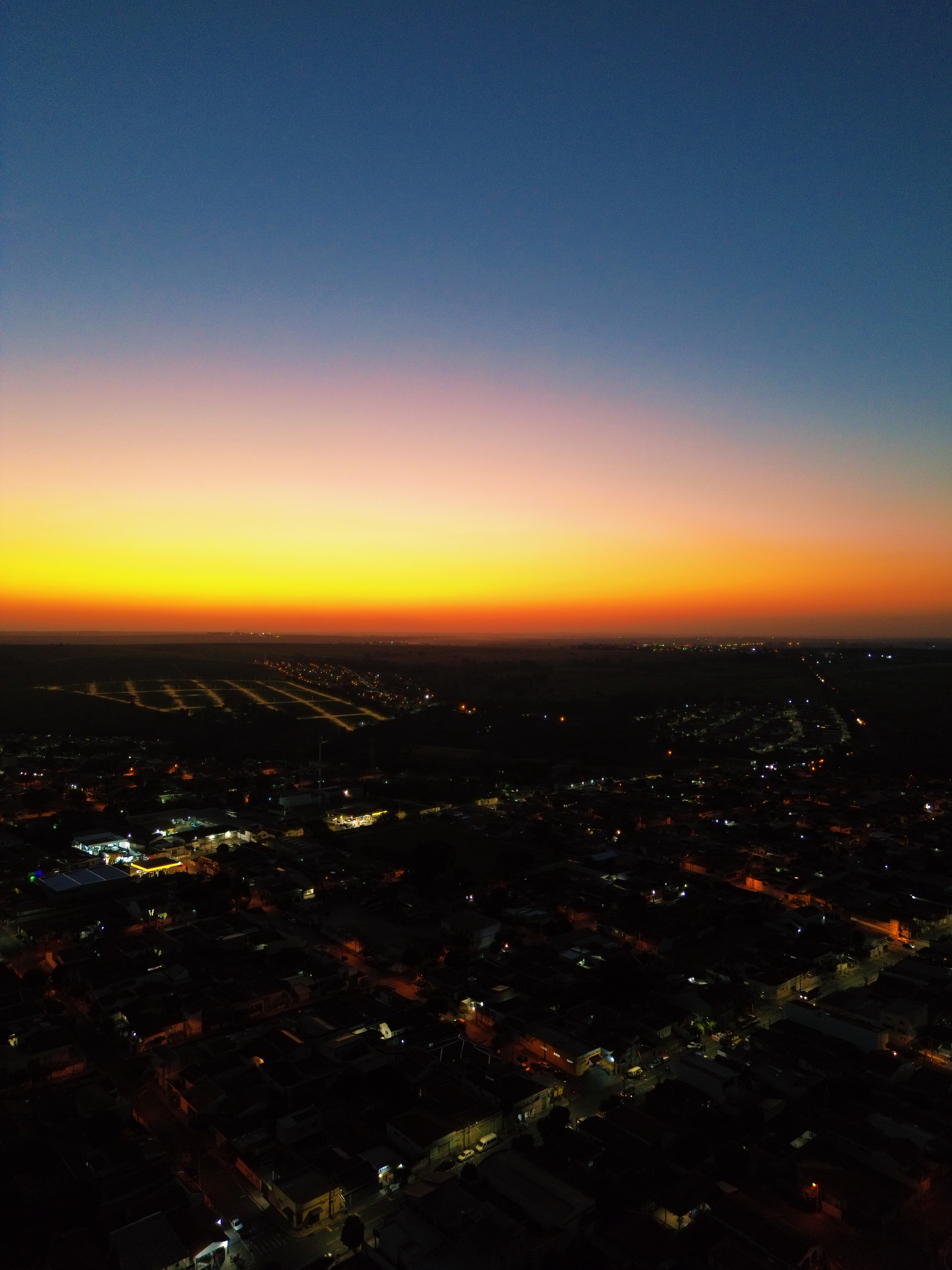 Vista aérea cinematográfica de praia tropical ao pôr do sol com tons de laranja e roxo